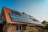 Ziegelhaus mit Solarmodulen auf dem roten Ziegeldach unter blauem Himmel.