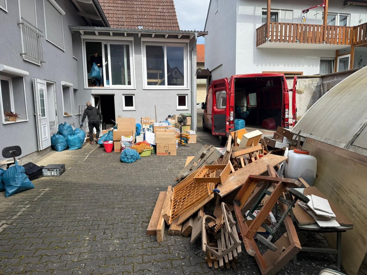 Hausentrümpelung durch FLEX Dienstleistungen: Möbel und Kartons im Hof, Transporter wird beladen
