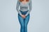 Woman holds pelvic area, indicating urinary incontinence concern.