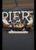 Vier Personen sitzen in einer Talkrunde vor einer Wand mit dem Schriftzug PIER 5. Text: Therapeuten beschreiben?