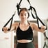 Junge Frau in Sport-BH und Leggings macht Übungen mit Schlingentrainern.