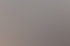 Eine lächelnde Frau mit lockigem Haar sitzt an einem Schreibtisch und arbeitet am Computer.