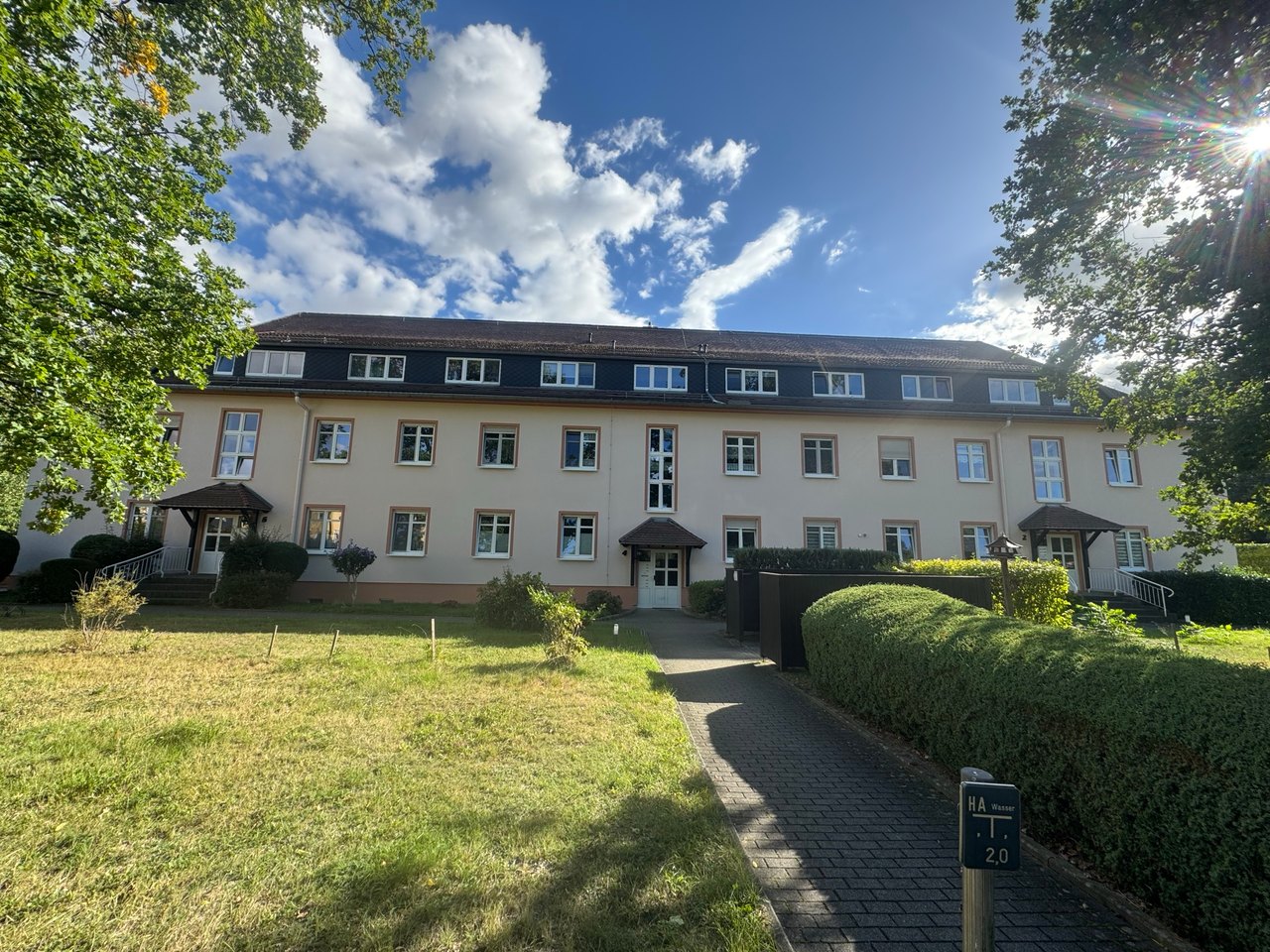 Vorderansicht des Mehrfamilienhauses mit Rasenfläche und Zugang zum Hauseingang