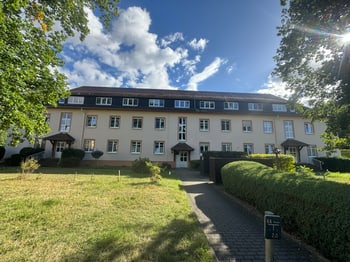 Vorderansicht des Mehrfamilienhauses mit Rasenfläche und Zugang zum Hauseingang