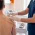 A healthcare provider applies TENS unit electrode pads to a patient's shoulder for electrical muscle stimulation therapy.