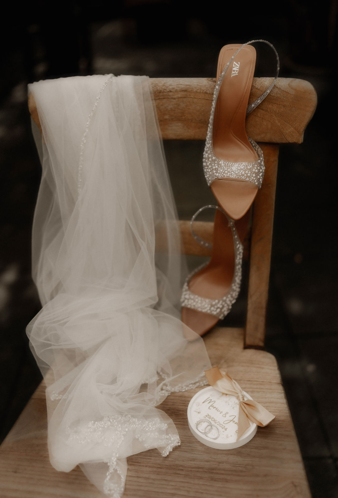 Brautschuhe mit Glitzer, Schleier und die Ringdose auf einem rustikalen Holzstuhl, ein Detail beim Getting-ready in der LaDü in Düsseldorf.