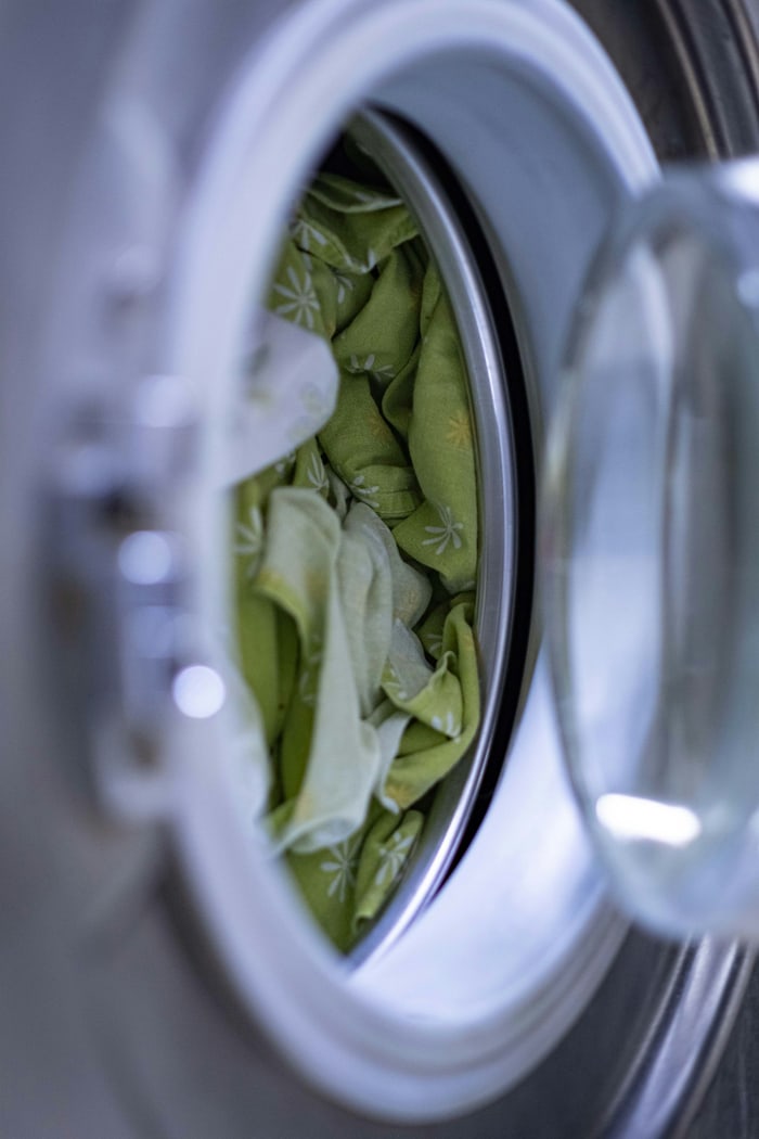 Blick in die Trommel einer Waschmaschine mit grüner Wäsche