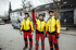 Drei Baumpfleger in Schutzkleidung blicken nach oben, einer zeigt mit dem Finger in den Himmel.