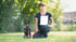 Frau mit kurzem Haar und Boxerhund auf einer grünen Wiese.