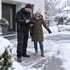 KB Cleaning Mitarbeiter mit Klemmbrett und Kundin besprechen den Winterdienst auf einem verschneiten Gehweg vor einem Wohnhaus.