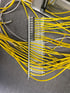 Ein Bündel gelber Kabel ist an einer Reihe von Steckverbindern befestigt, die auf einem grauen Boden liegen.