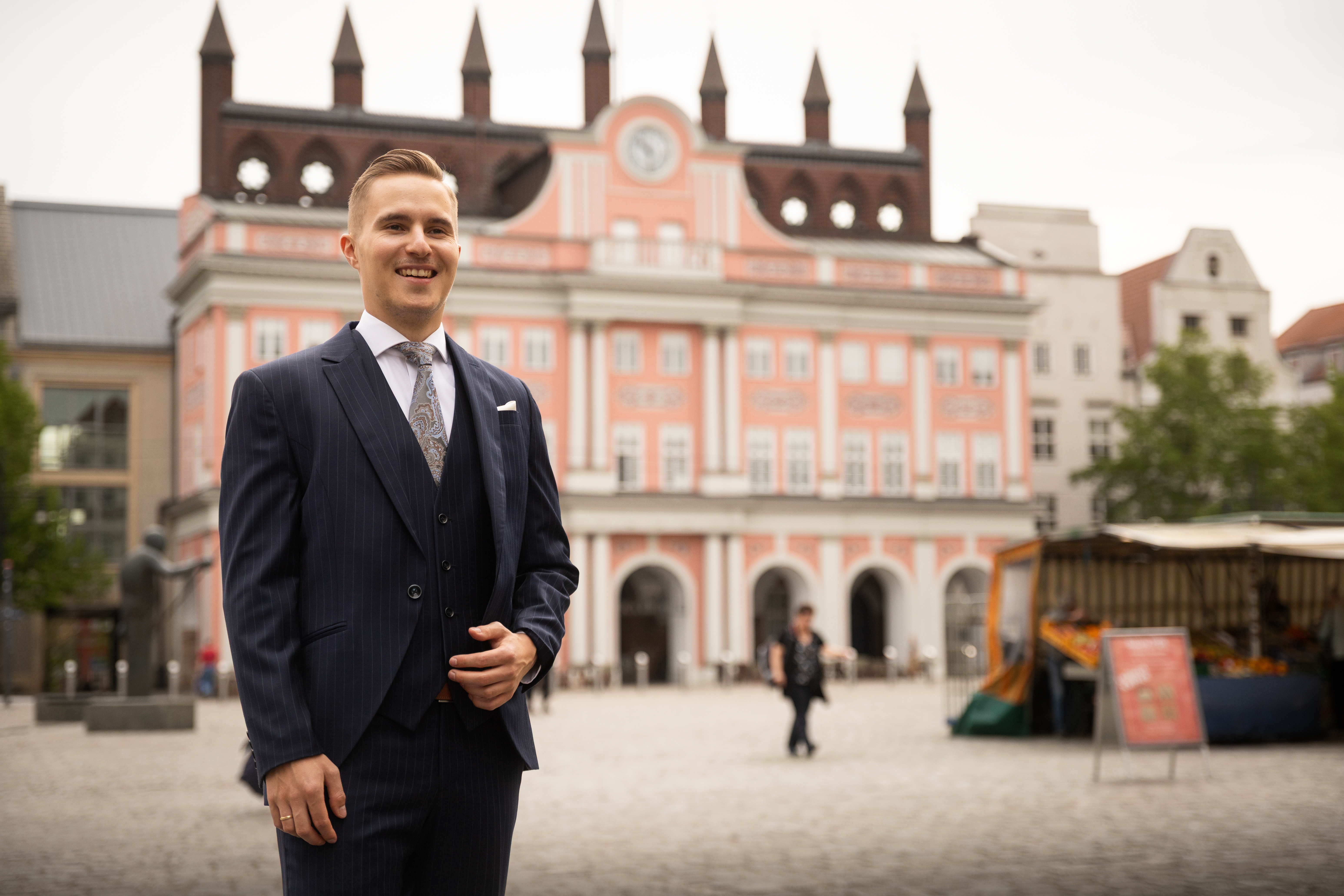 Ein Modell eines geschnittenen Zahns mit Karies steht vor einem Zahnarzt, der einen Patienten behandelt.