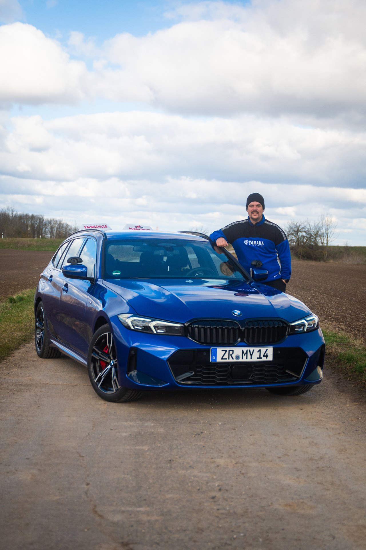 Basti mit einem modernen blauen BMW Fahrschulwagen der Full Motion Fahrschule in Gera