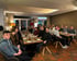 Gruppe junger Erwachsener sitzt an Tischen in einem Restaurant und blickt in die Kamera.