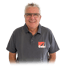 Hartwig Gehr mit grauen Haaren und Brille trägt ein graues Poloshirt mit dem "Gehr"-Logo.