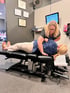 A chiropractor adjusts a patient lying face up on a black examination table.