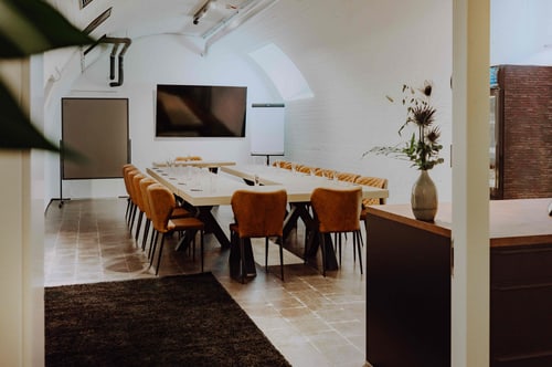Gewölbekeller mit langem Konferenztisch, Bildschirm und Whiteboard
