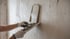 Hände in weißen Handschuhen tragen Putz mit einer Glättkelle auf eine unfertige Wand auf