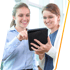 Two women smile while reviewing medical services on a tablet together.