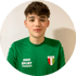 Porträt eines jungen Mannes mit braunen Haaren im grünen Sporttrikot von Eintracht Emmerich vor weißer Wand.