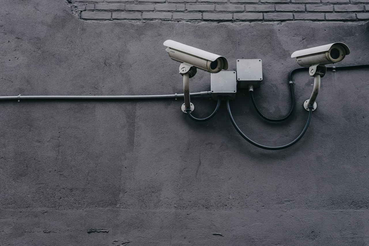 A white security camera mounted on the exterior wall of a home