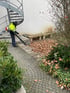 Mitarbeiter mit Laubbläser bei der Laubentfernung im Rahmen der Kehrarbeiten und Grünpflege