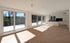 Heller, leerer Wohnraum mit Holzboden, großen Fenstern, Zugang zu einem Balkon und einer weißen Küchenzeile.