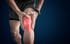 Person holding a knee with a glowing red area, indicating knee pain or injury.