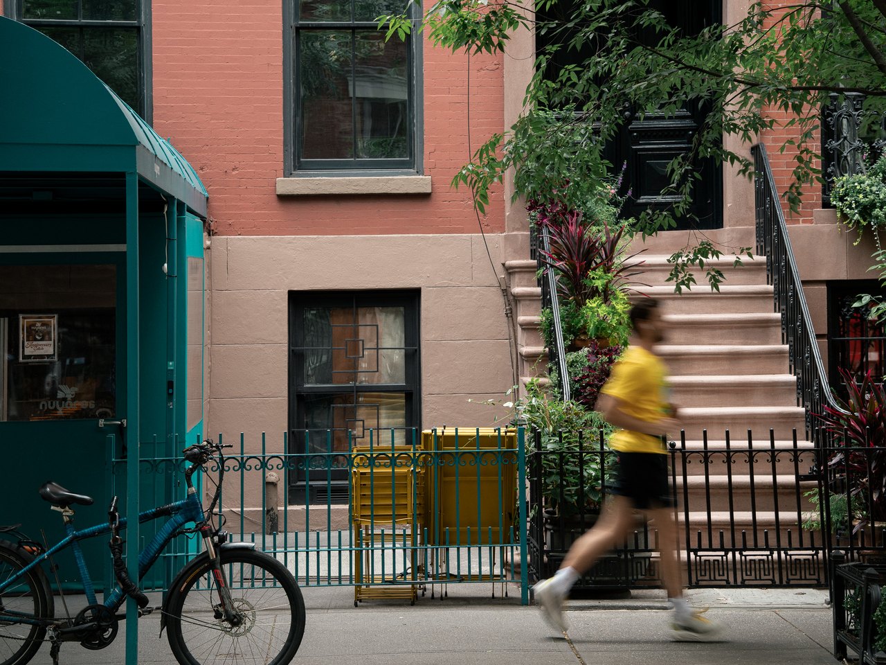 Runner in a yellow shirt passing a brownstone stoop, New York