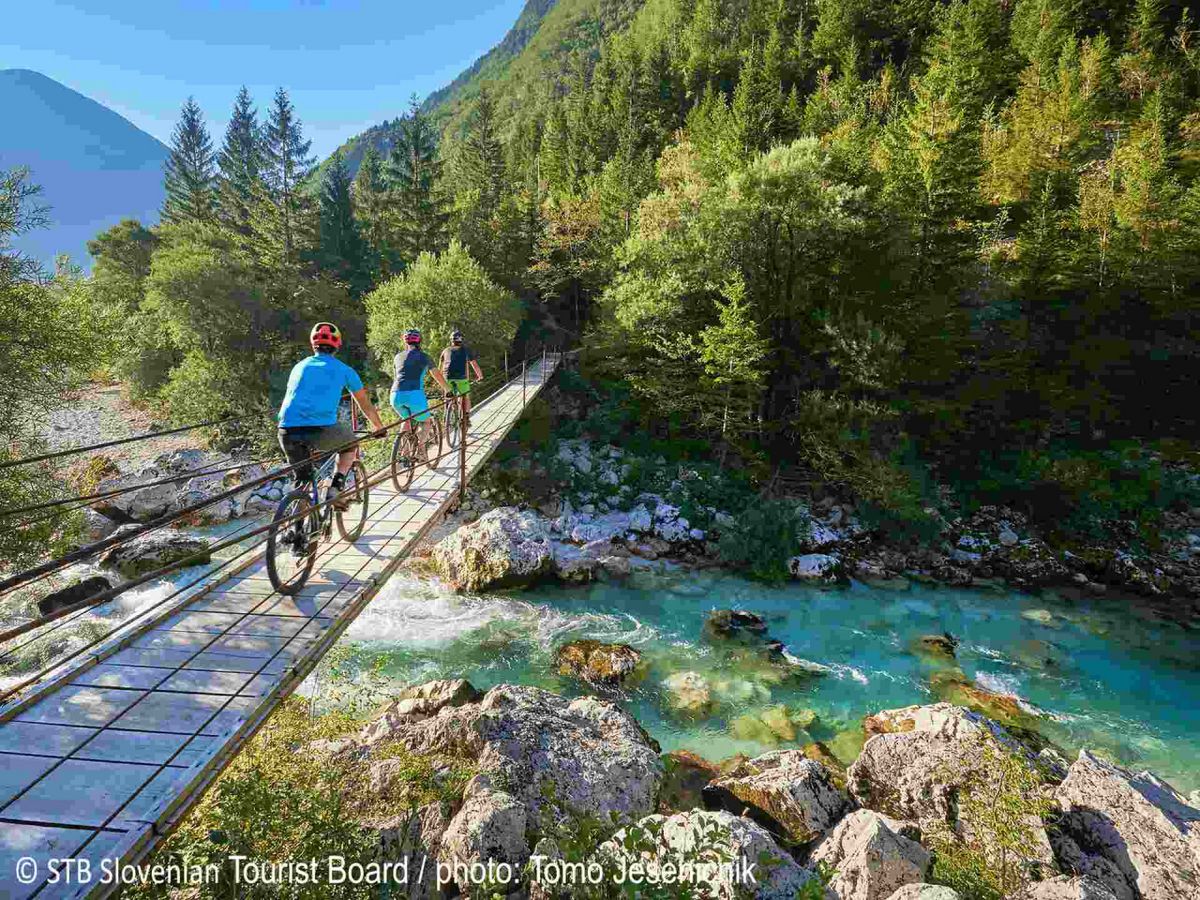 Radfahrer auf einer Hängebrücke über einen Gebirgsfluss, Motiv der Radreisen