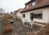 Hinterhofterrasse mit Grill und Gartenmöbeln vor einem Haus mit Dachgauben.