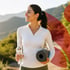 Acupuncture wellness patient smiles outdoors holding yoga mat and water bottle