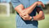 Man holds elbow outdoors, showing discomfort from elbow pain.