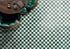 Boden mit grün-weißem Schachbrettmosaik, daneben Tisch und grüner Ledersessel von oben