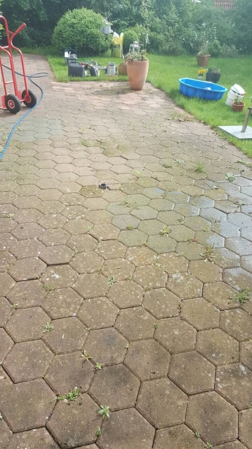 Terrasse aus Sechseck-Pflaster mit Moos vor der Reinigung