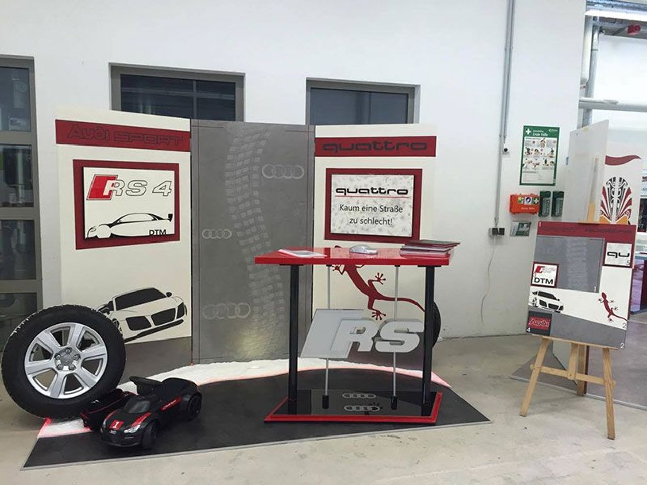 Audi Quattro Stand mit RS4-Logo, einem roten Stehtisch, Reifen und Slogan: Kaum eine Straße zu schlecht.