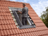 Dachdecker montiert ein Dachfenster in einem roten Ziegeldach.