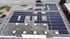 Dach eines Gebäudes mit zahlreichen Solarpanels und Oberlichtern.