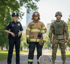 Polizistin, Feuerwehrmann und Soldat stehen nebeneinander im Park.