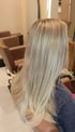 Langes, glattes Haar mit hellblonden Highlights und Balayage-Effekt von hinten in einem Friseursalon gesehen.