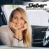 Lächelnde blonde Frau mit den Händen am Kinn sitzt im Auto. Sieber Automobile GmbH & Co. KG Logo oben rechts.