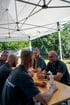 Das Mitarbeiter von Singer und Singer sitzen gemeinsam an einem Holztisch unter einem weißen Pavillon im Freien.