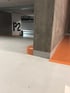 Tiefgarage mit weißem Boden, grauen Wänden und Säulen, orangefarbenen Markierungen und der Aufschrift "P2".