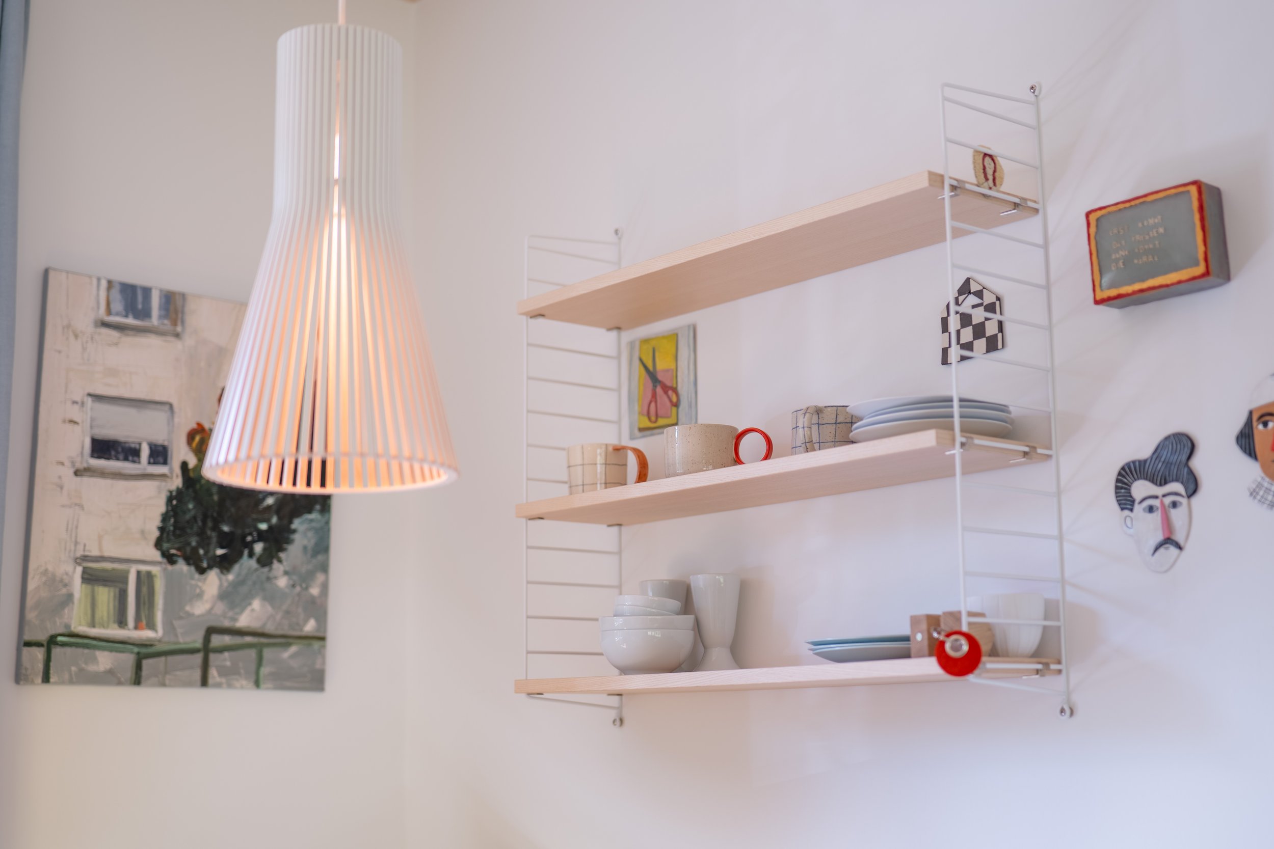 Offenes Regal mit Geschirr, Büchern und Bildern im Wohnraum
