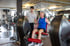 Ein Fitnesstrainer betreut einen älteren Mann beim Training an einer Beinstrecker-Maschine im Fitnessstudio.