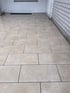 Beigefarbene Bodenfliesen in Steinoptik im versetzten Verband verlegt auf einer Terrasse oder einem Balkon.