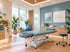 Moderner Behandlungsraum für Physiotherapie mit blauer Therapieliege, Gymnastikball und Wandposter „Lebensqualität“.