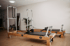 Zwei Pilates-Reformer aus Holz mit Metallrahmen stehen nebeneinander in einem hellen Studio mit Parkettboden.