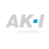 AK-I Immobilien Logo: Graue Buchstaben "AK-I", blaues Quadrat im I, darunter "Immobilien" auf grünem Hintergrund.