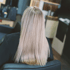 Eine Frau mit langen, glatten, blonden Haaren sitzt mit dem Rücken zur Kamera in einem Friseurstuhl.